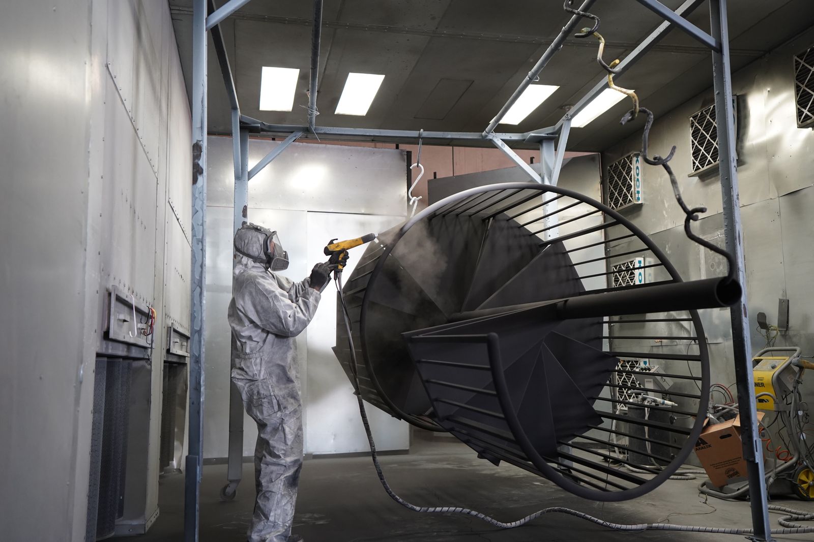 Technician applying powder coating to a metal structure
